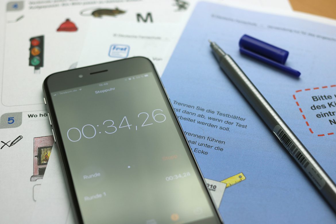 Ein Handy mit aktivierter Stoppuhr liegt auf Testblättern