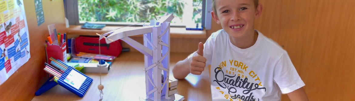 Boy with crafted crane gives a thumbs up